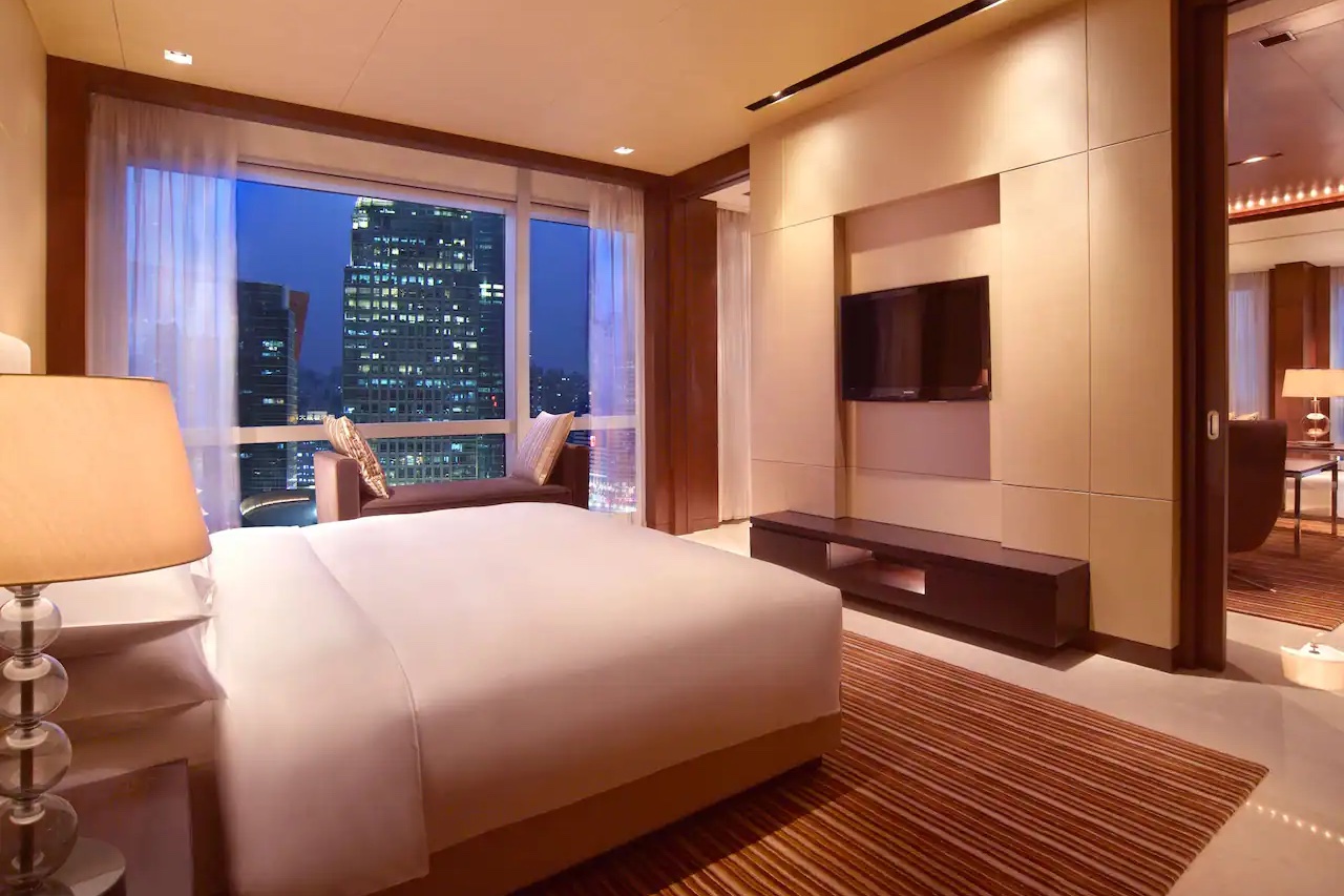A hotel room with a large window looking out onto a cityscape