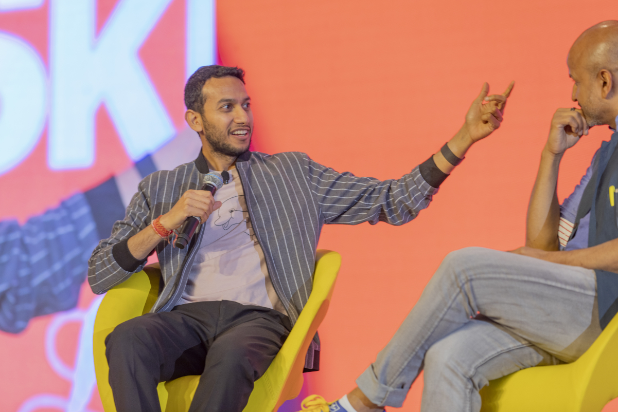 two men speak on a stage