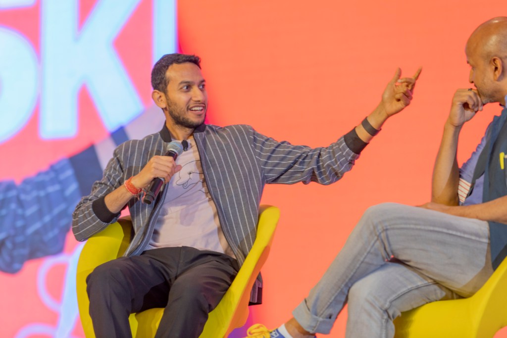 two men speak on a stage