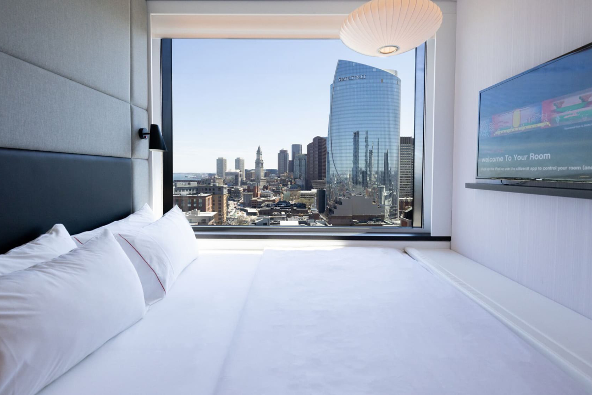 king size bed in a tiny citizenm room with a view of city through window